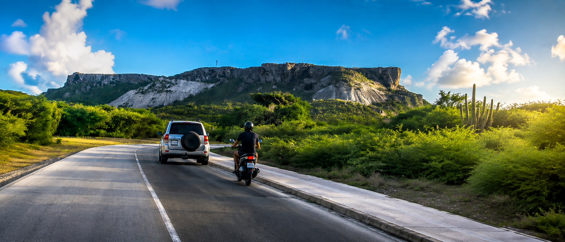 Rental SUV and scooter exploring a road in Curaçao